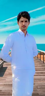 Man standing on a boardwalk by the serene blue ocean and sky.