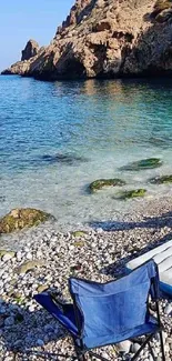 Serene beach with clear blue water and a beach chair on a rocky shoreline.