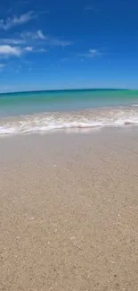 Serene beach wallpaper with golden sand, gentle waves, and blue sky.