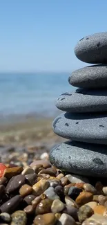 Stack of pebbles on a beach with a clear blue sky and ocean view.