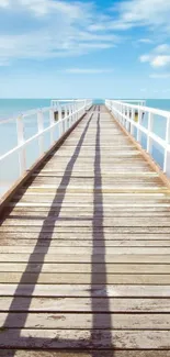 Tranquil wooden pier extending into the ocean with a blue sky background.