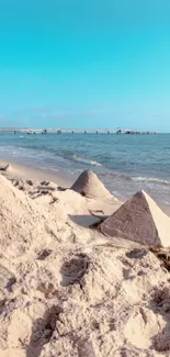 Beach with sand pyramids and a clear blue sky.