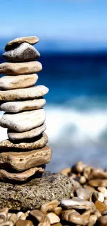 Stacked rocks by the ocean with a serene beach backdrop.