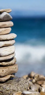 Stacked stones with ocean backdrop, serene beach wallpaper.