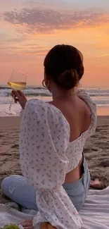 Woman enjoys sunset on a serene beach with wine.