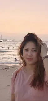 Woman enjoying a serene beach during a pink sunset.