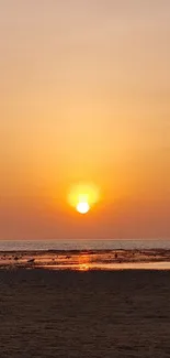 Serene sunset over ocean with orange skies.