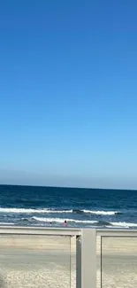 Tranquil beach view with ocean waves and a blue sky mobile wallpaper.