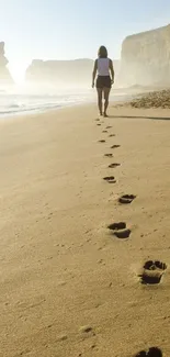 Woman walks on sandy beach leaving footprints into the horizon.