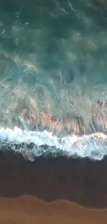 Aerial view of ocean waves crashing onto a sandy beach, creating a serene coastal scene.