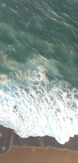 Aerial view of gentle beach waves meeting the sandy shore with blue-green ocean hues.