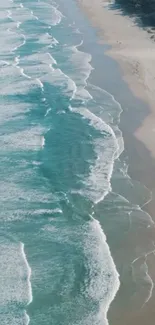 Aerial view of tranquil beach waves meeting the sandy shore on a sunny day.