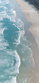 Aerial view of sparkling waves on a tranquil sandy beach with turquoise waters.