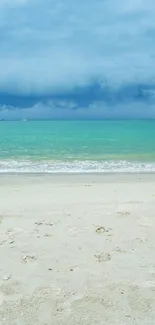 Turquoise ocean waves and sandy beach under a cloudy sky.