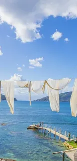 A peaceful sea view with white curtains and a clear blue sky.