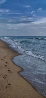 Mobile wallpaper of a serene beachside with footprints and blue skies.