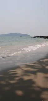 Tranquil beach wallpaper with gentle waves and island view.