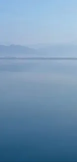 Serene blue lake with misty mountains.