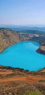 Bright blue lake surrounded by cliffs under a clear sky.