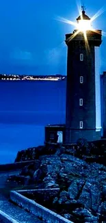 Serene blue lighthouse overlooking the ocean at night.