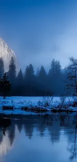 Serene blue mountain landscape with misty peaks and a tranquil water reflection.