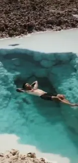 Person relaxing in a serene natural blue pool.