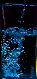 Water pouring into glass with blue bubbles, set against a dark background.