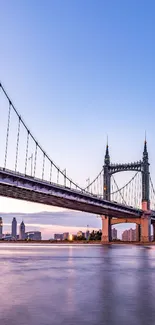 Bridge over calm water during sunset with a cityscape in the background.