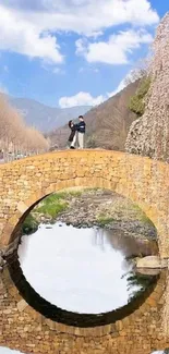 Stone bridge over a calm reflective river under a bright blue sky.