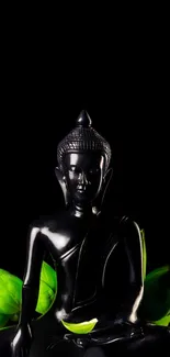 Black Buddha statue with green leaves on black background.