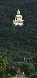 White Buddha statue in lush green mountain on mobile wallpaper.