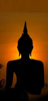 Silhouette of Buddha against a vibrant sunset sky with amber hues.