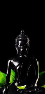 Black Buddha statue with green leaves on a black background.