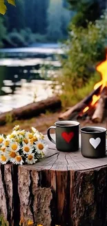 Two mugs with hearts by campfire and lake.