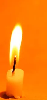 Candle with glowing flame against vibrant orange background.