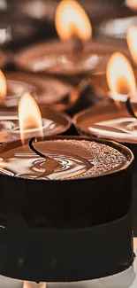 Glowing candles creating a warm, serene atmosphere as a mobile wallpaper background.