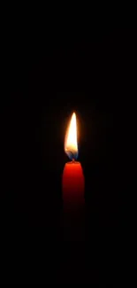 A single lit red candle against a dark background.