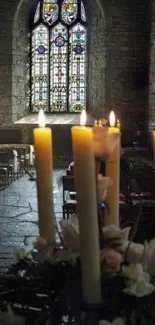 Candles illuminate a serene church with stained glass windows.