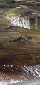 Cascading waterfall over rocks with serene natural scenery.