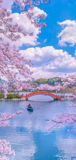 Cherry blossoms and red bridge beside a tranquil lake under a blue sky.