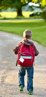 A young boy with a red backpack walking down a peaceful, tree-lined path.