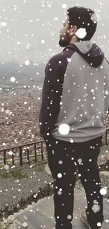 Person standing and overlooking a cityscape surrounded by mountains.