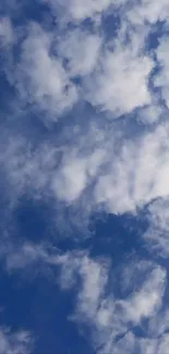 Fluffy white clouds against a blue sky, perfect for a serene phone wallpaper.