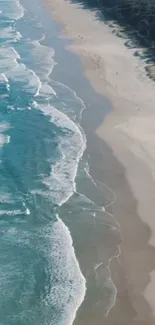 Aerial view of turquoise ocean waves meeting a sandy beach with lush greenery.