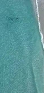 Aerial view of turquoise ocean meeting a sandy beach.