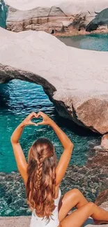 Woman relaxing by turquoise sea with rocky coastline.