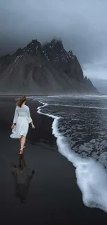 Woman walks along a serene coastal beach with majestic mountains.