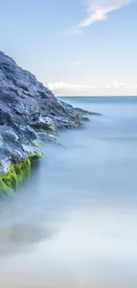 Serene coastal rock mobile wallpaper with light blue sea.