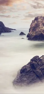 Coastal rocks with a misty blue sea and dramatic cloudy sky background.