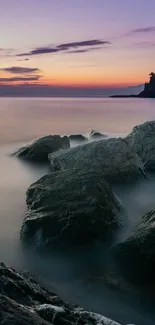 Serene coastal sunset with violet sky and rocky shoreline.